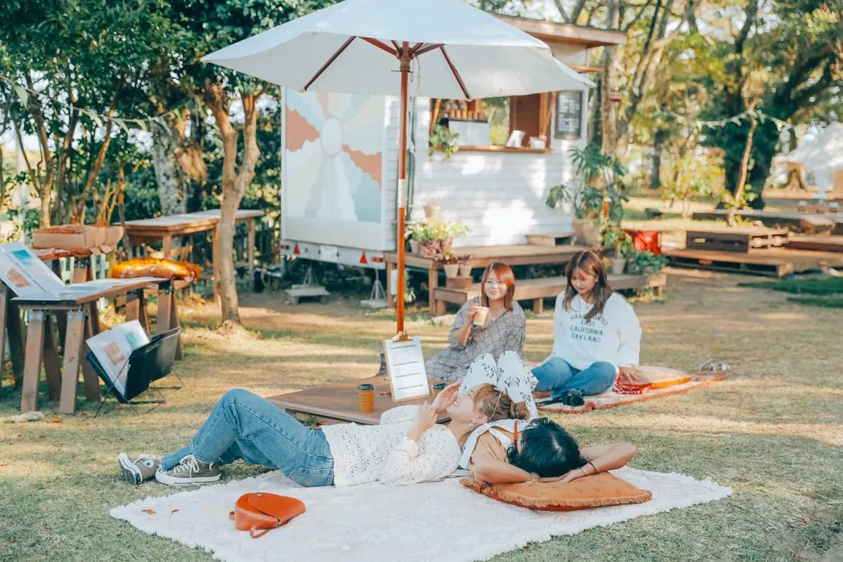 芝生にラグを敷いて寝転ぶメンバーと Byron Bay Coffee の店舗