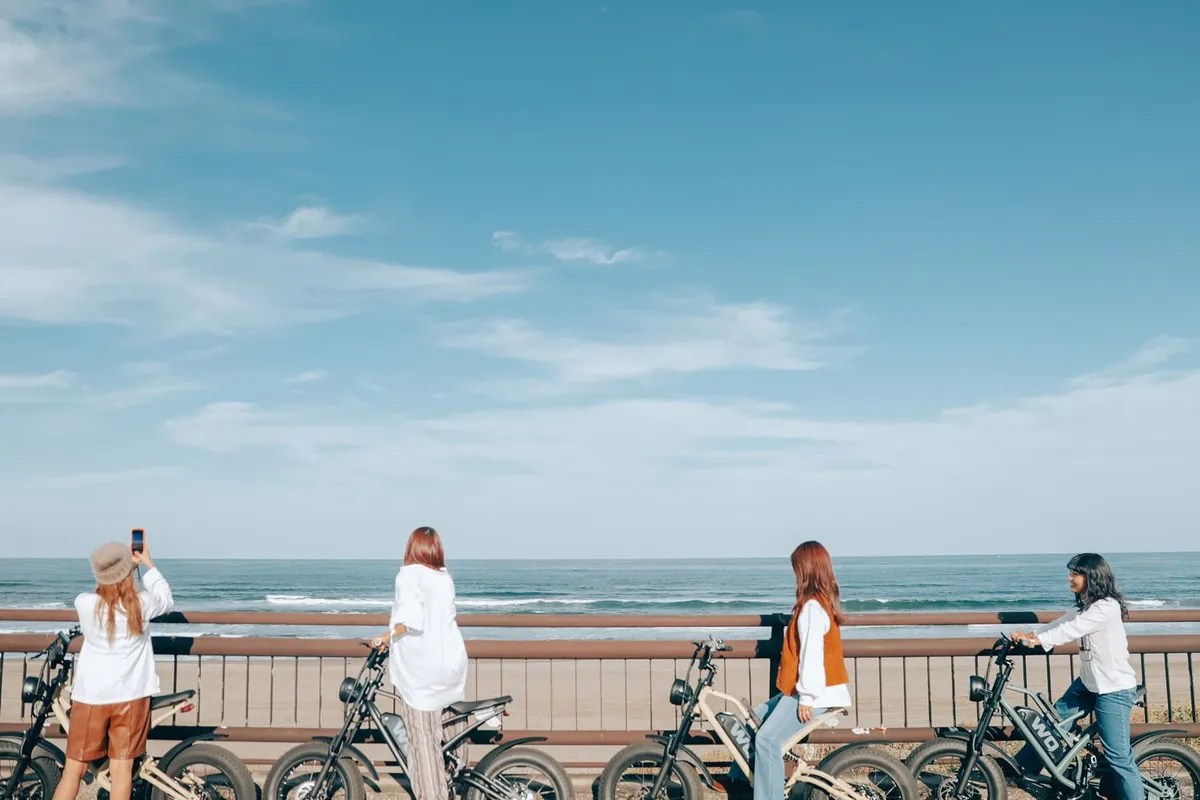 海を背に E-BIKE を停めて写真を撮るメンバー