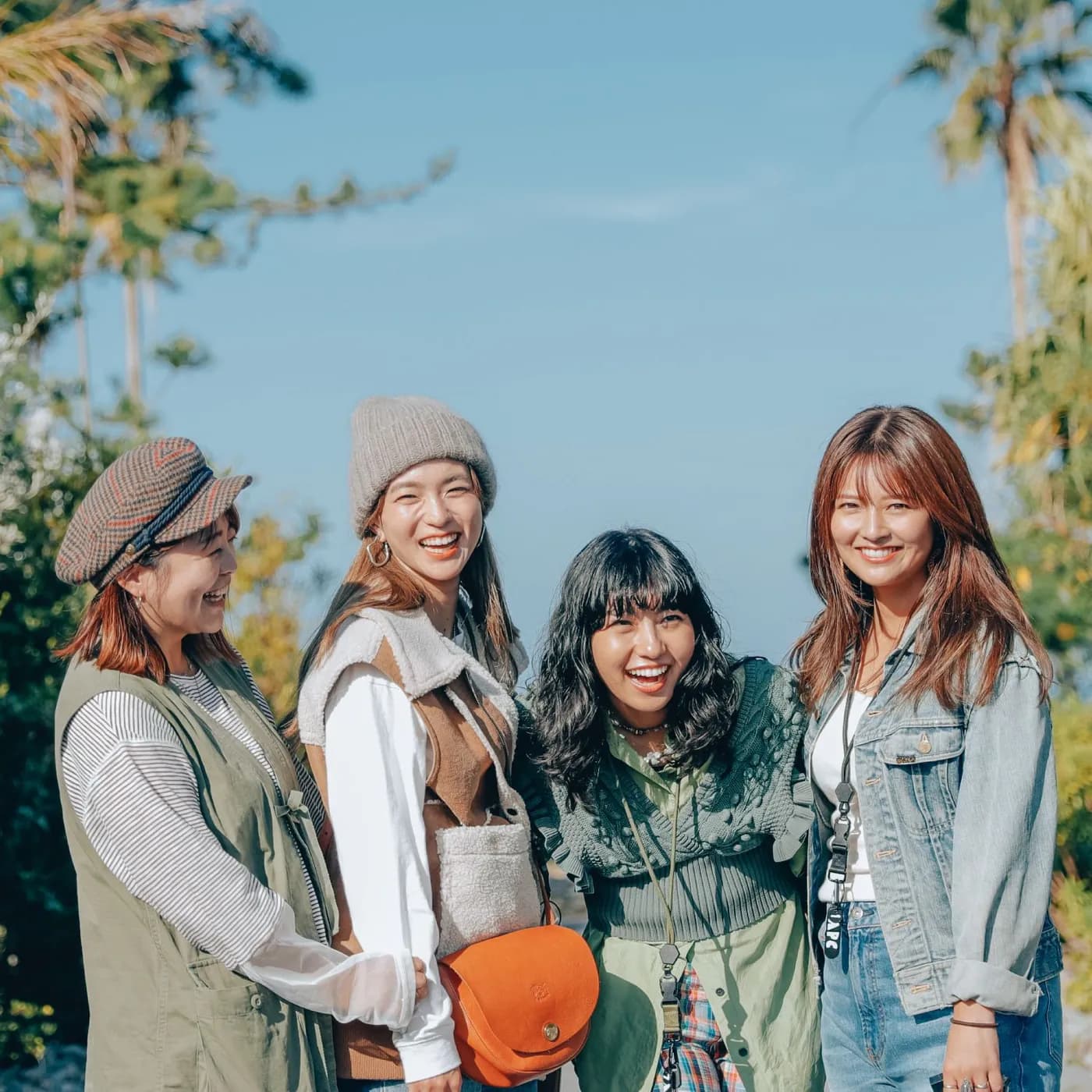 ヤシの木を背に並んで笑う Sunny Side Camp のメンバー4人
